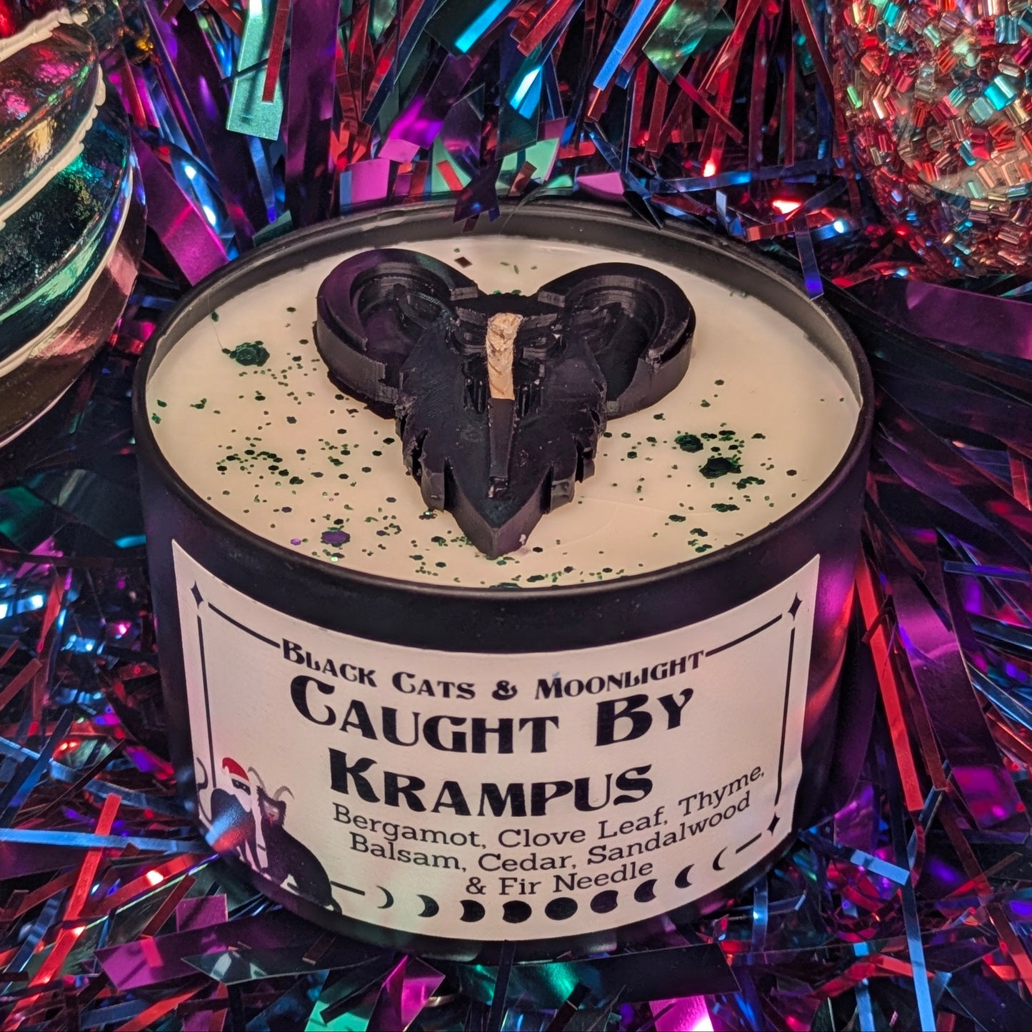 Candle with a Krampus decoration on top, surrounded by colorful tinsel