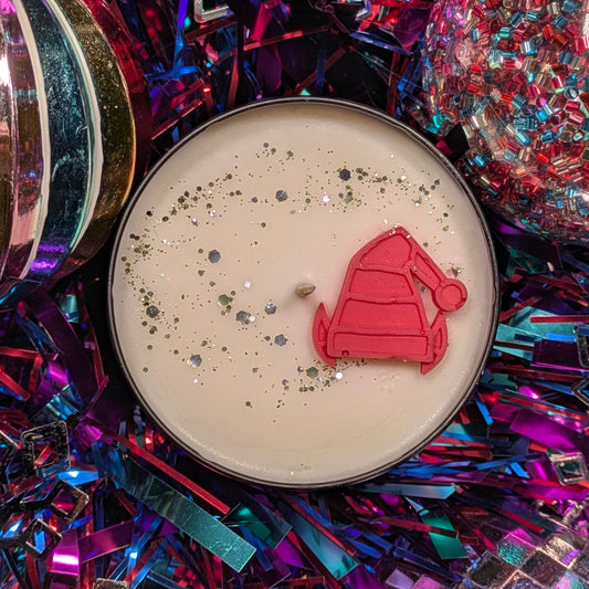 Candle with an elf hat decoration on a colorful, glittery background