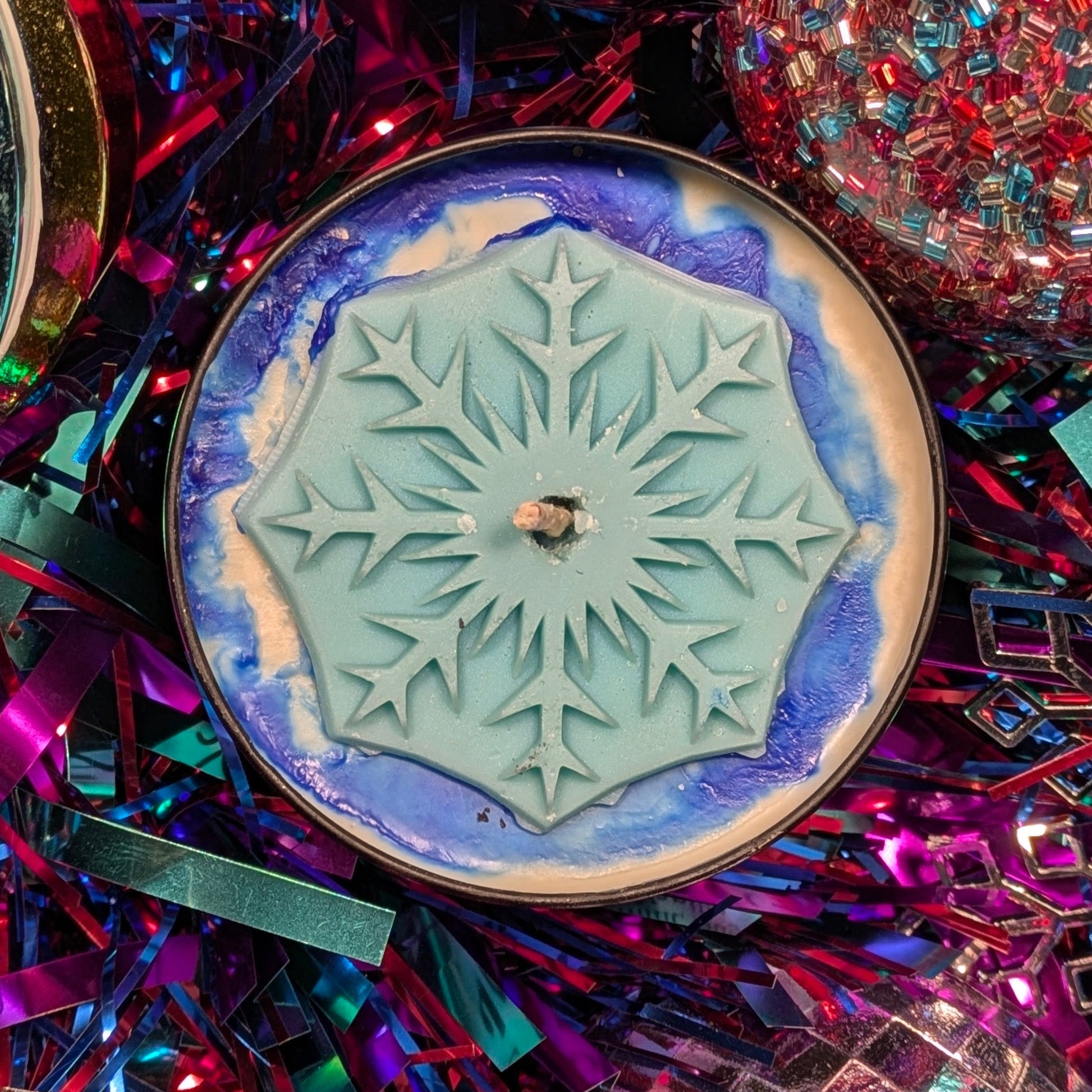a candle with snowflake design on a colorful, festive background