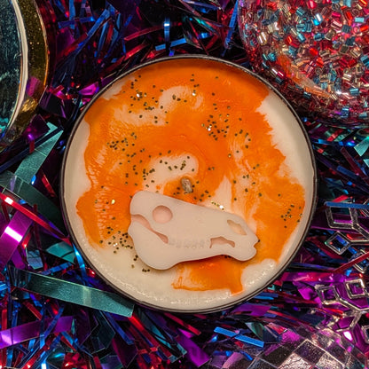A candle with a decoration of a horse skull and an orange glittery top