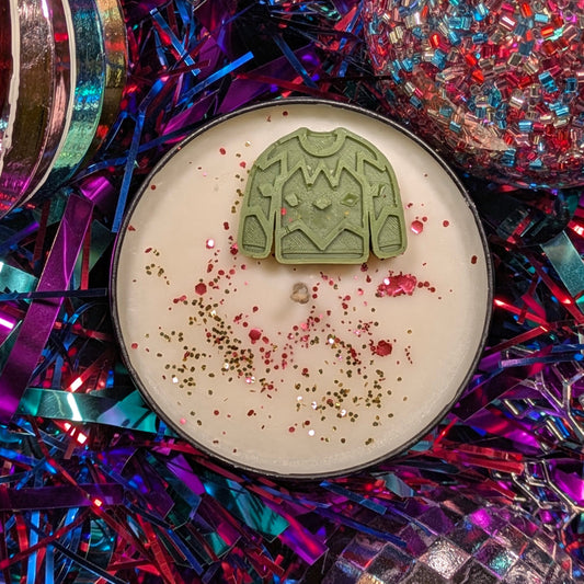 Candle with a green jumper-shaped decoration on a colorful, festive background