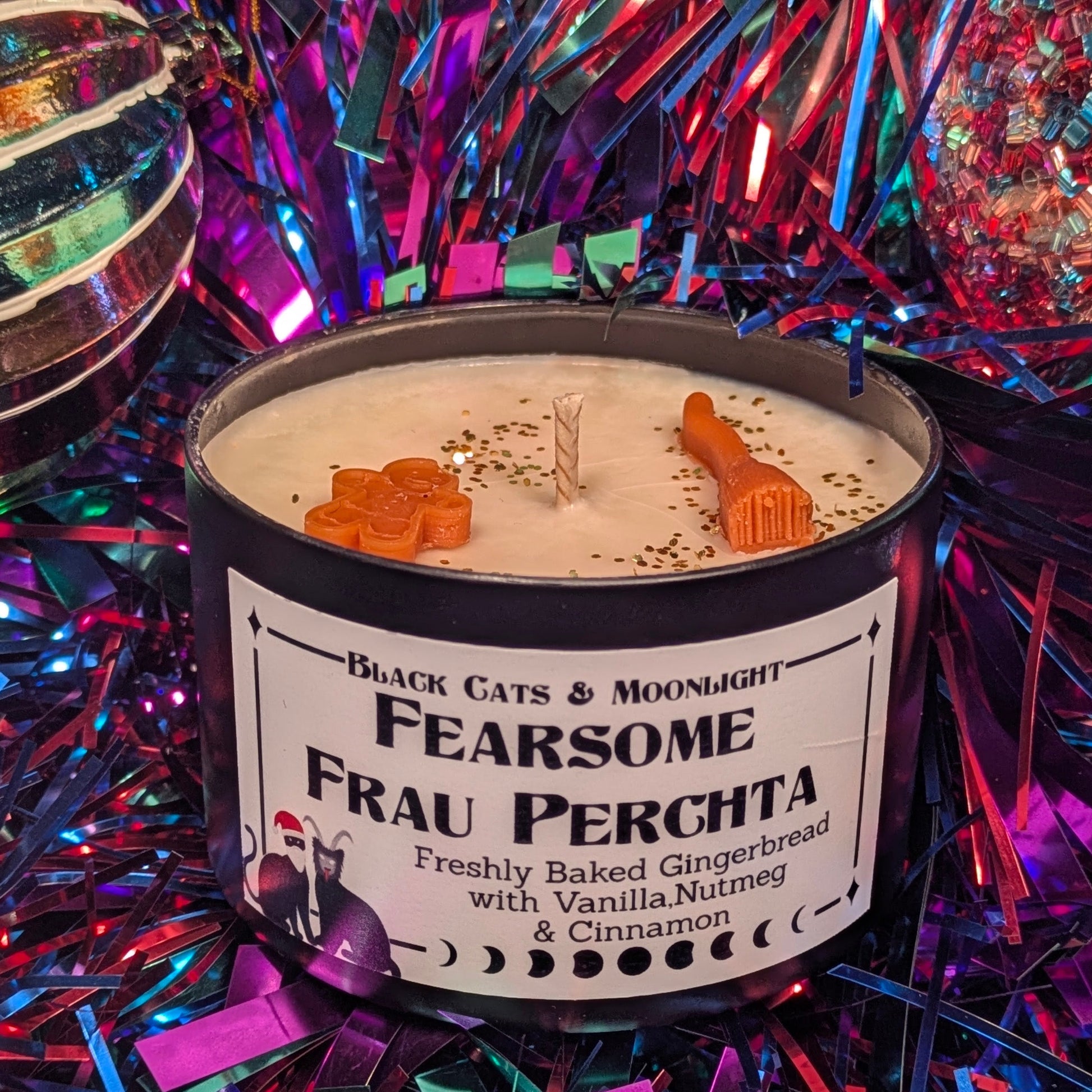 Candle labeled 'Fearsome Frau Perchta' on a festive background with tinsel.