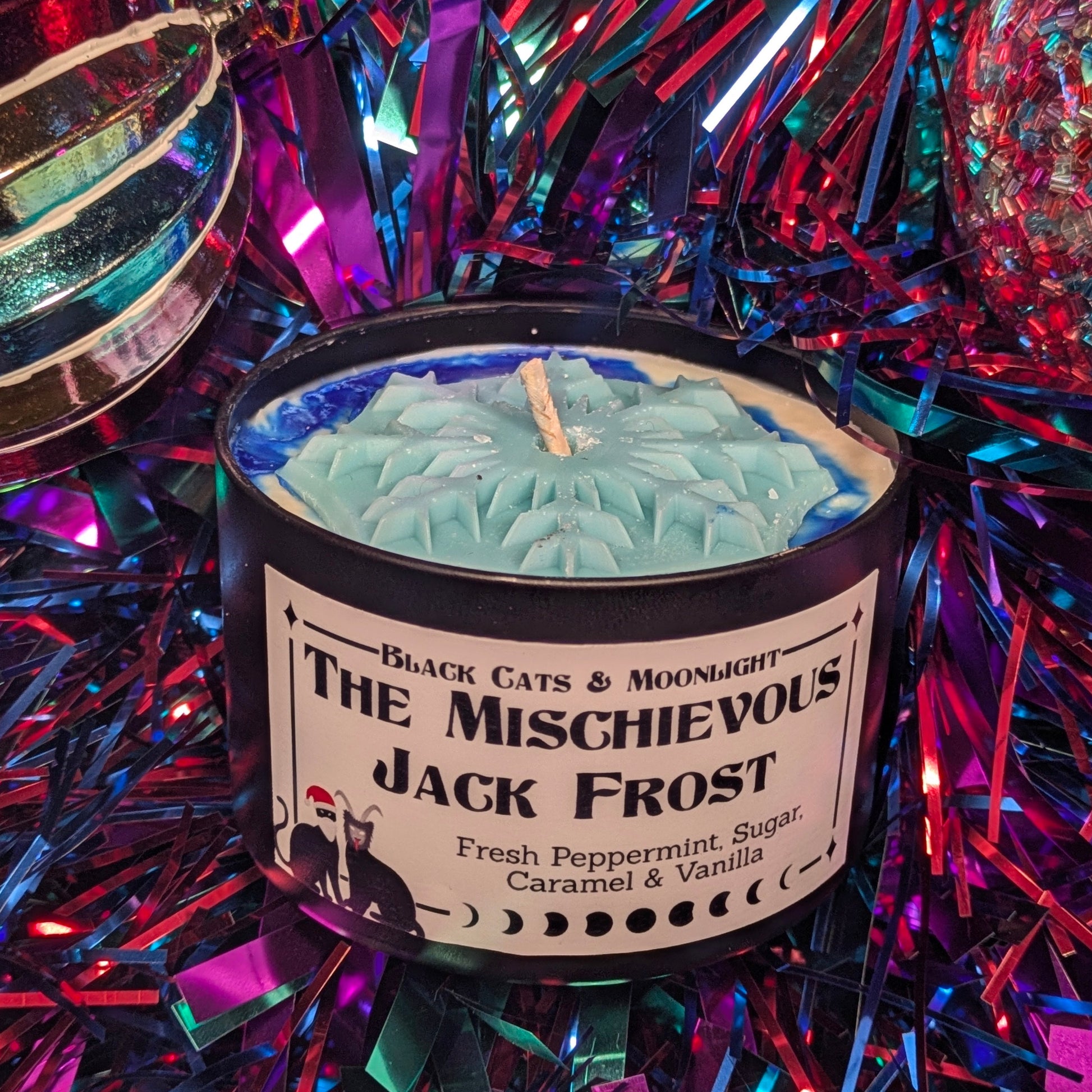 Candle labeled 'The Mischievous Jack Frost' surrounded by festive tinsel.